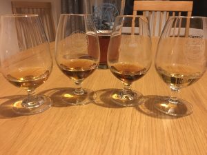4 drams of whisky with beer in the background